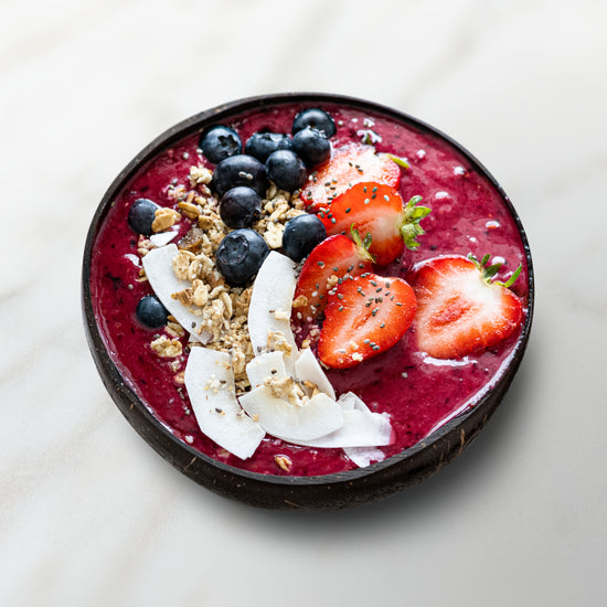 smoothie bowl avec un smoothie rouge, fraise, myrtilles, noix de coco et céréales