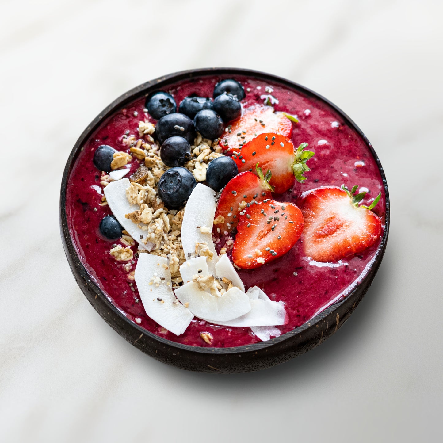 smoothie bowl avec un smoothie rouge, fraise, myrtilles, noix de coco et céréales