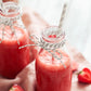 Smoothie rose dans des petites bouteilles en verre avec une paille accompagnées de fraise