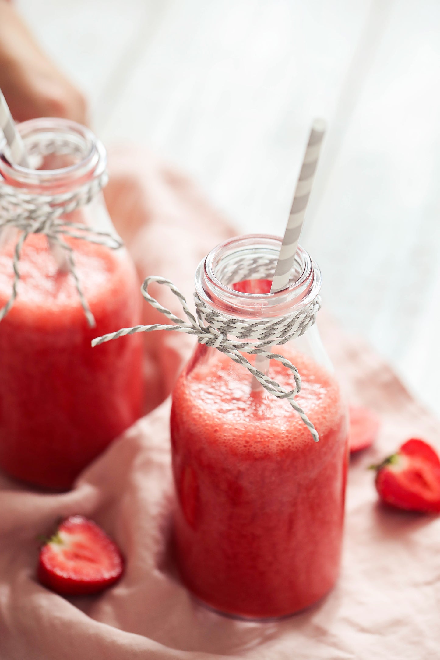 Smoothie rose dans des petites bouteilles en verre avec une paille accompagnées de fraise
